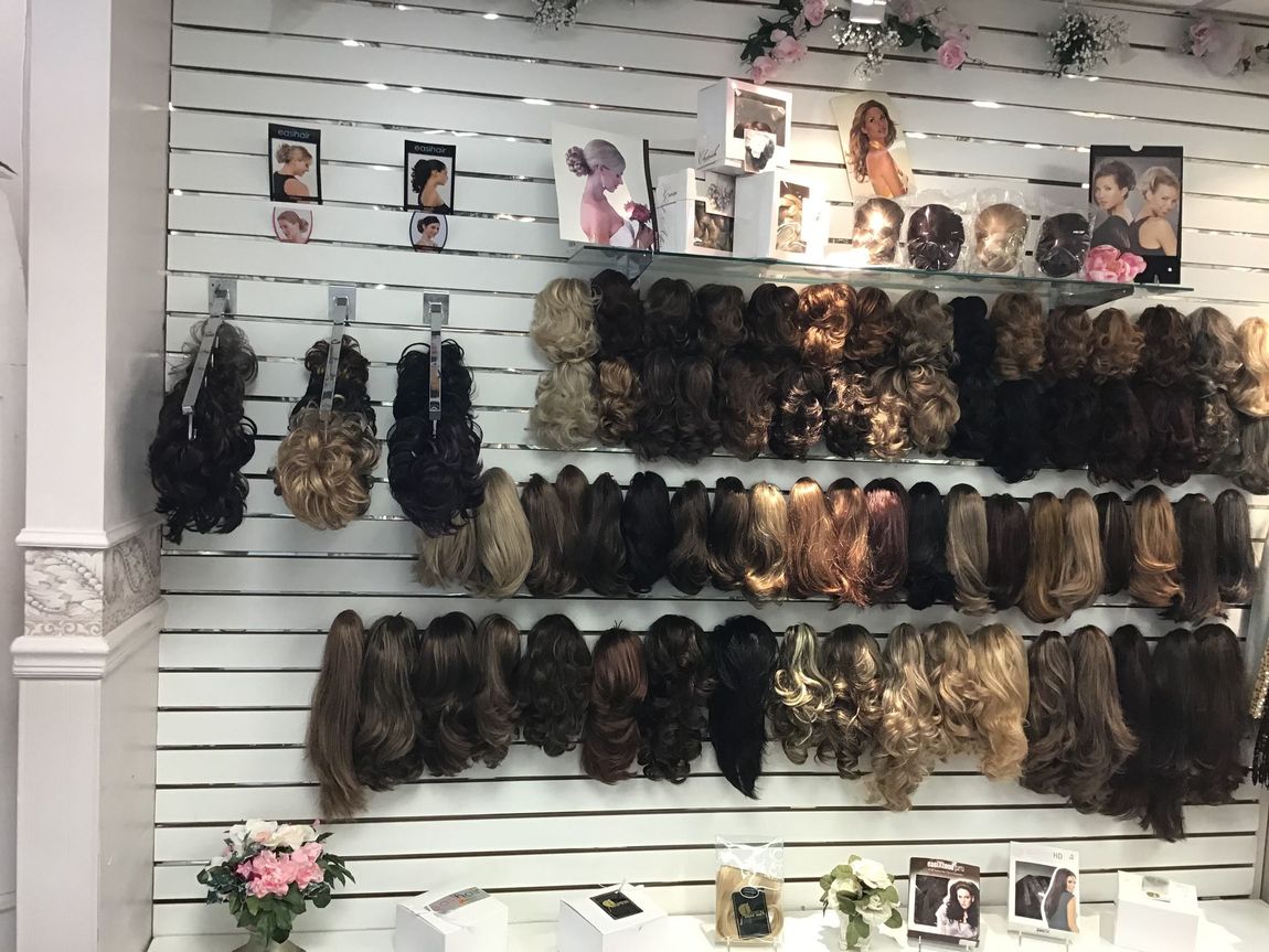 A wall with a lot of wigs hanging on it