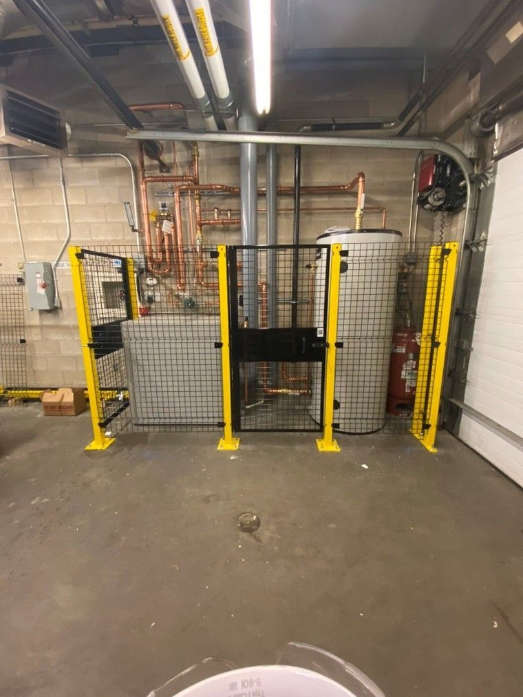 Yellow and black safety barriers around equipment in an industrial basement setting.