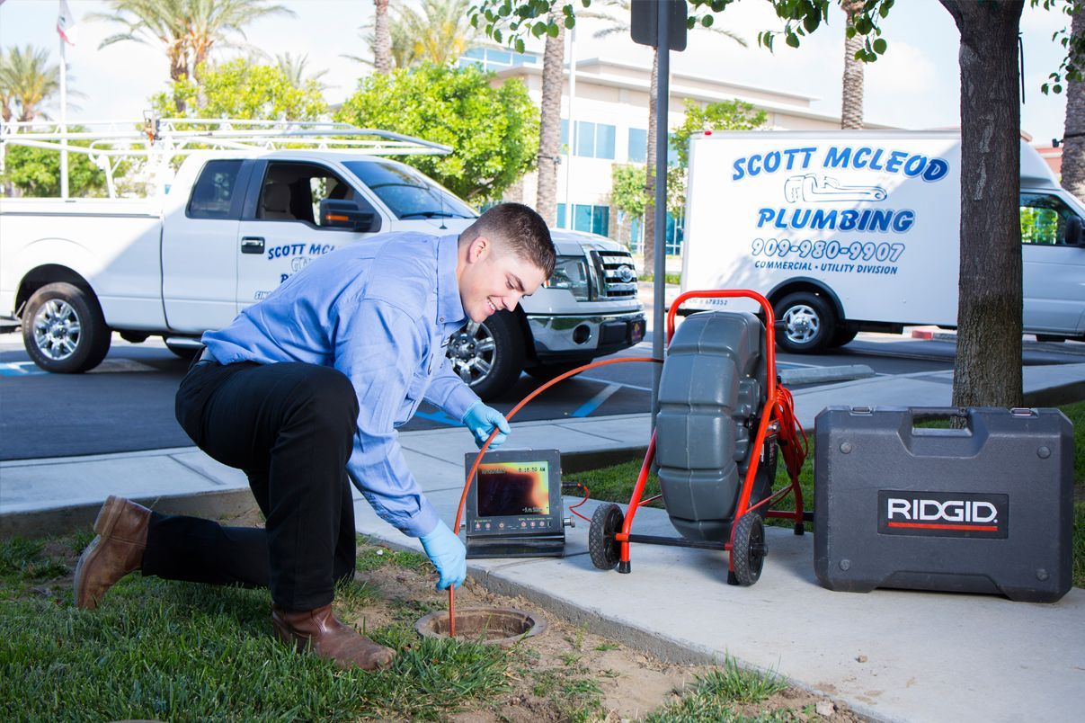 A man is kneeling down in front of a plumbing truck.