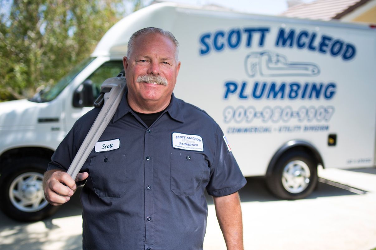 A man holding a pipe in front of a scott mcleod plumbing van