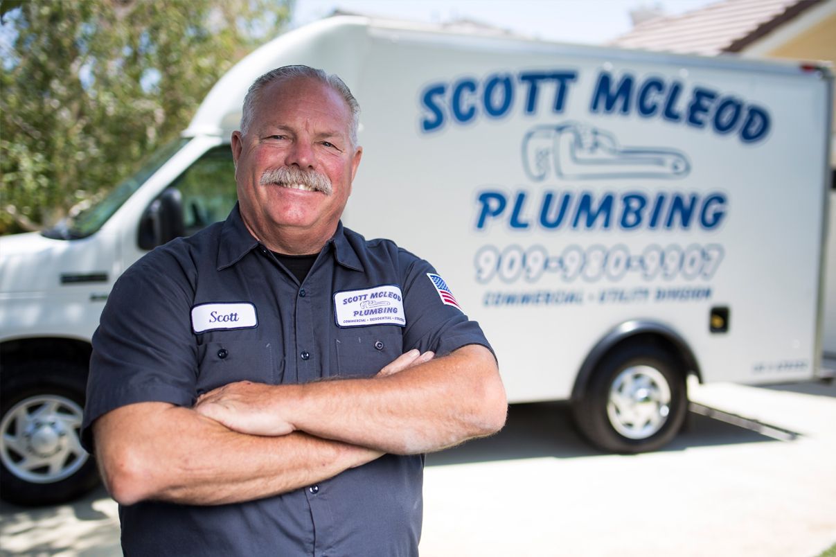A man is standing in front of a plumbing truck.