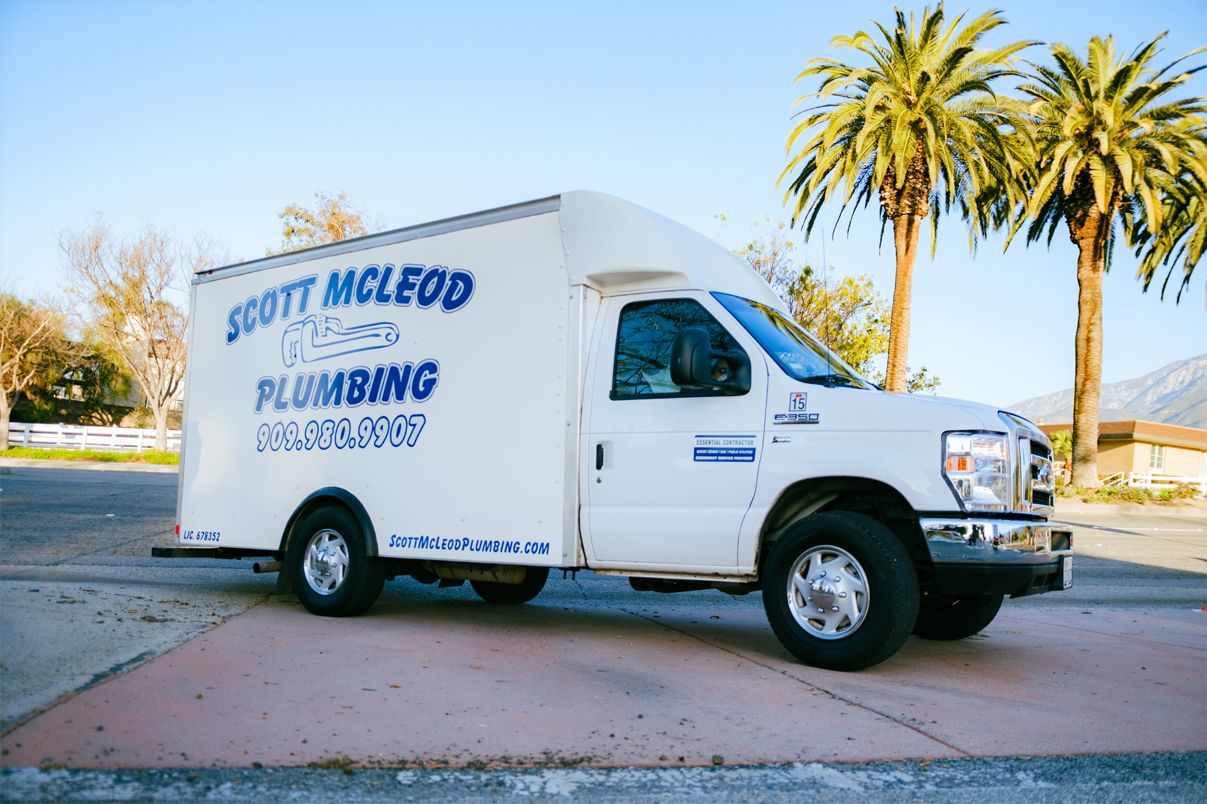 A white plumbing truck is parked on the side of the road.