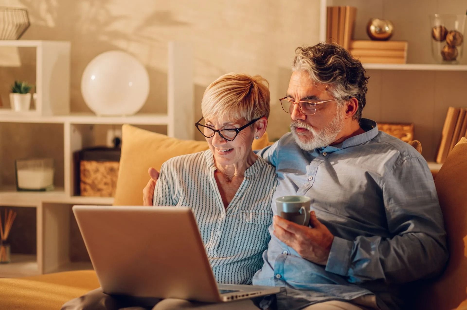 Two people on a couch using a laptop and phone in a cozy living room