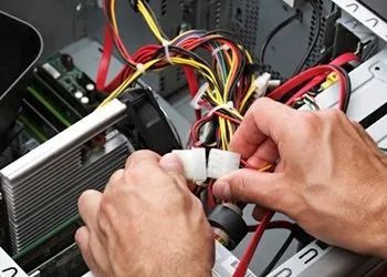 Hands connecting white power cables inside a desktop computer case with visible red and yellow wires.