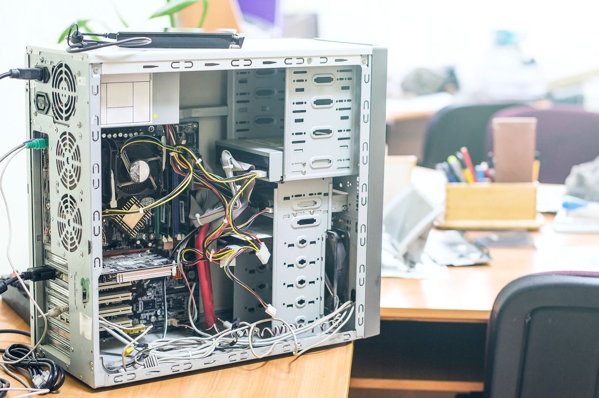 Open desktop computer case with exposed wires on a desk in an office setting
