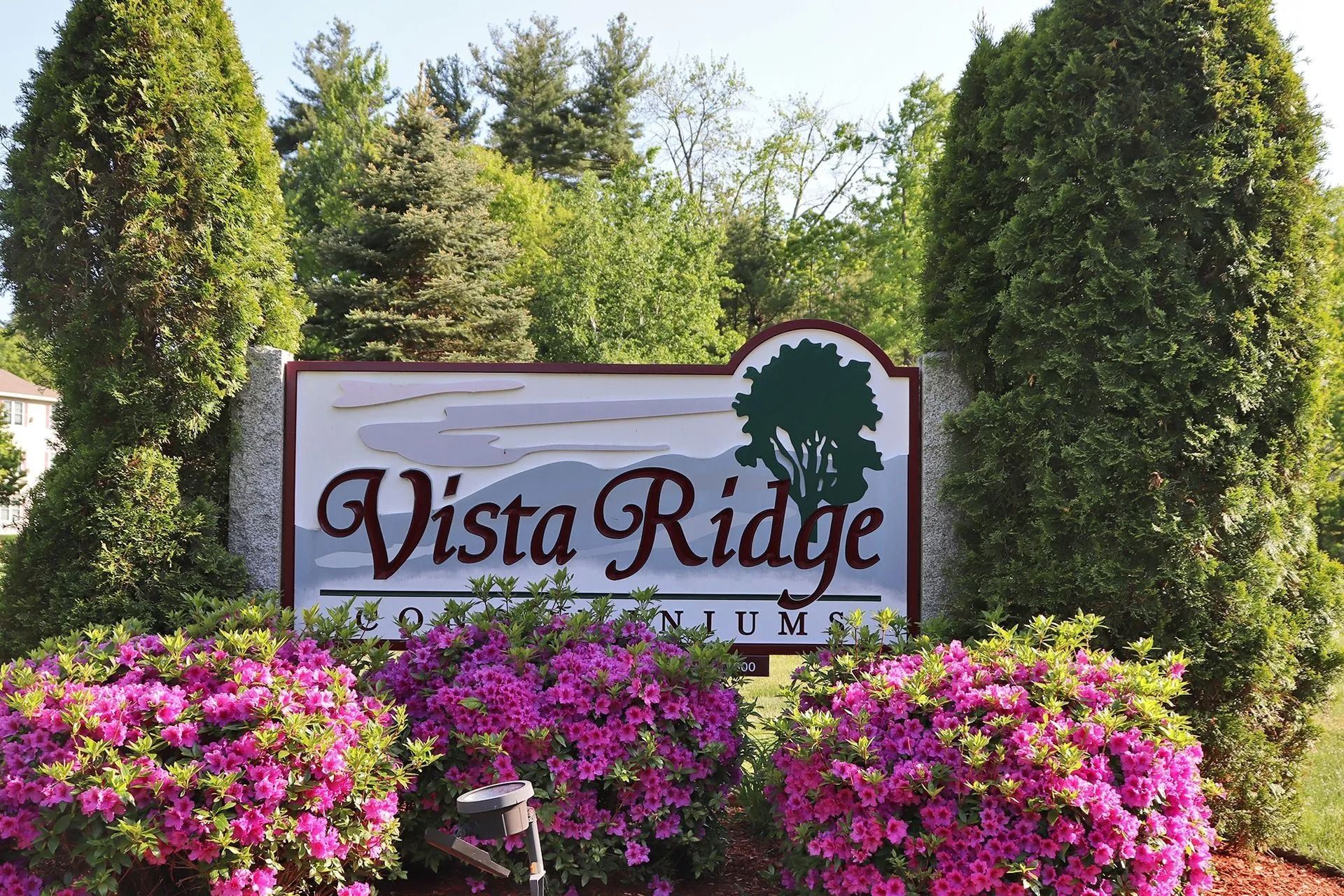 Vista Ridge Condominiums sign with pink flowers and green trees.