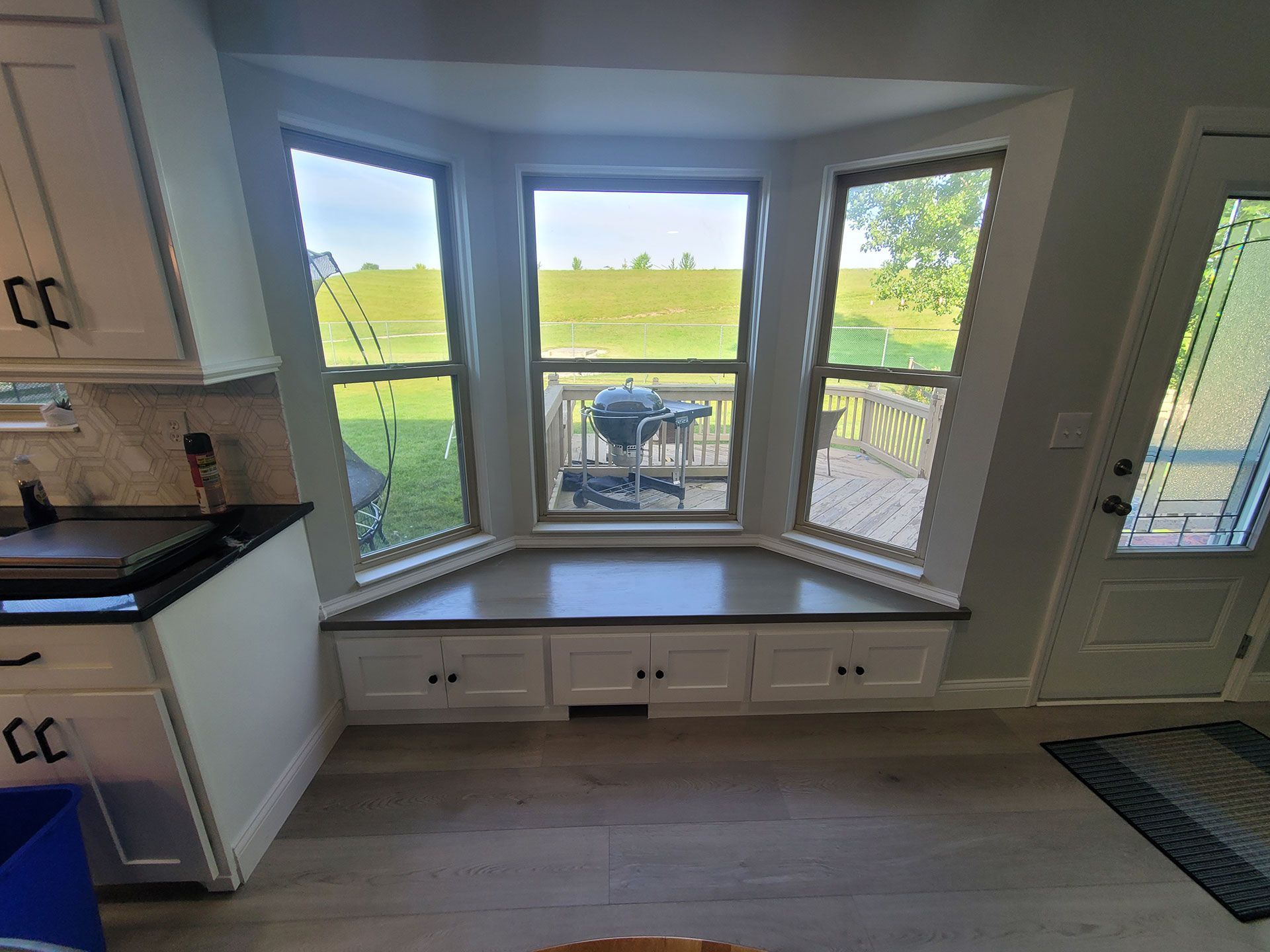 Kitchen bay window with built-in bench seating and cabinets. View of a lake through the windows.