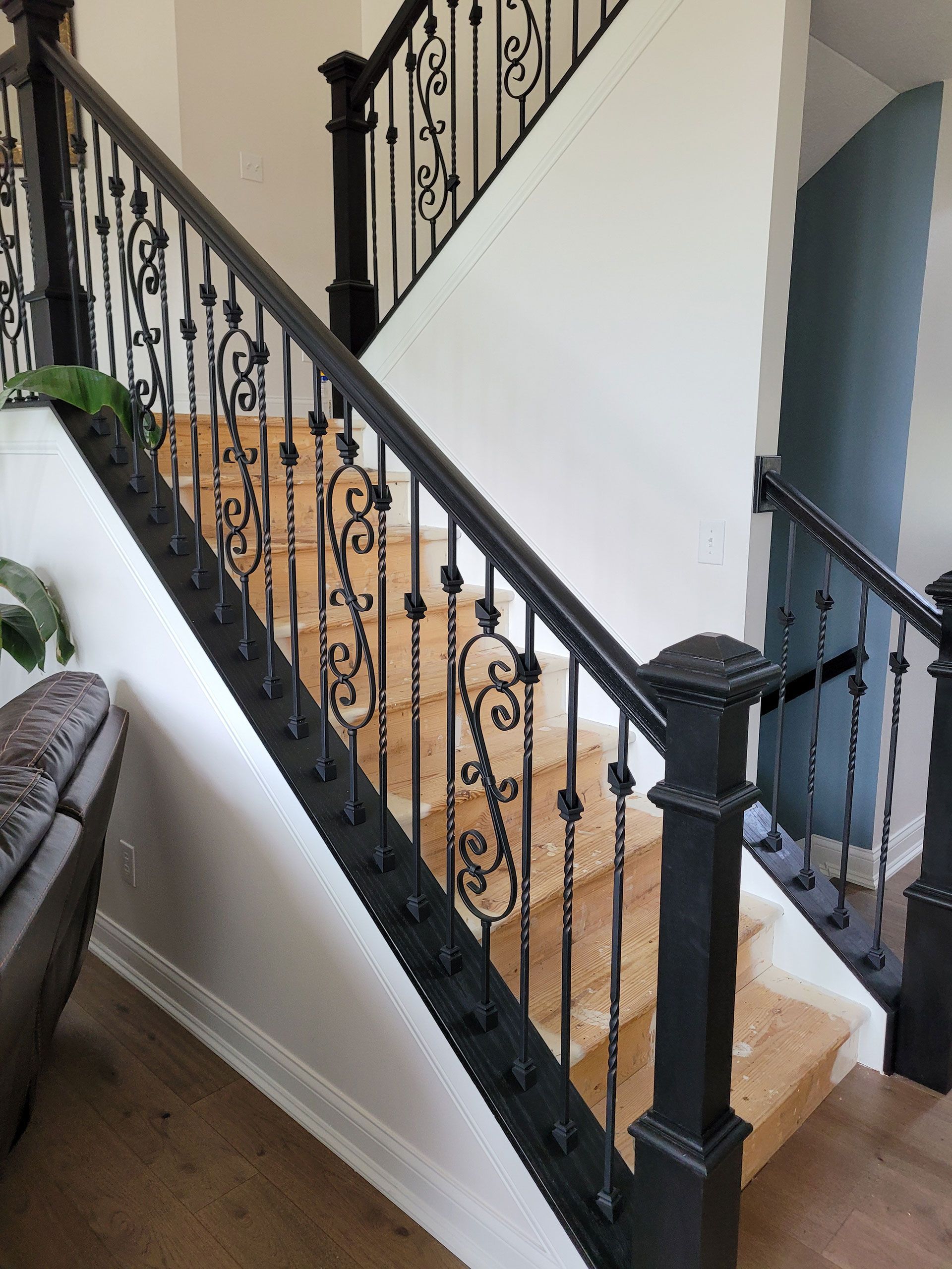Black metal railing along wooden staircase, white and blue walls.