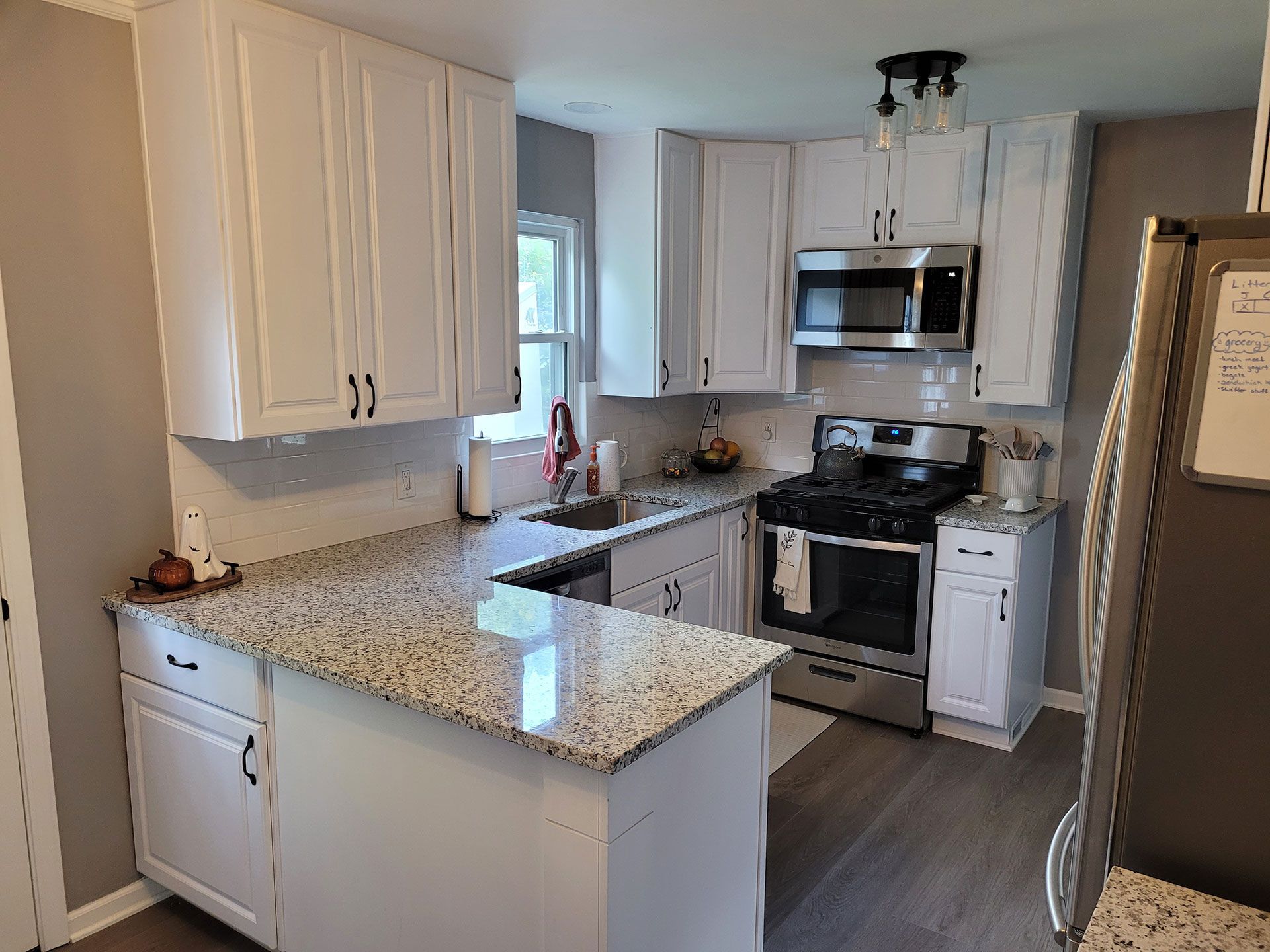 White kitchen with granite countertops, stainless steel appliances, and gray walls.