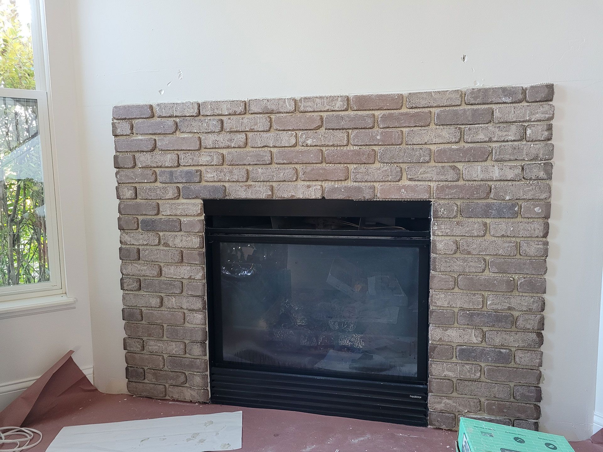 Brick fireplace surround with black firebox and glass doors.