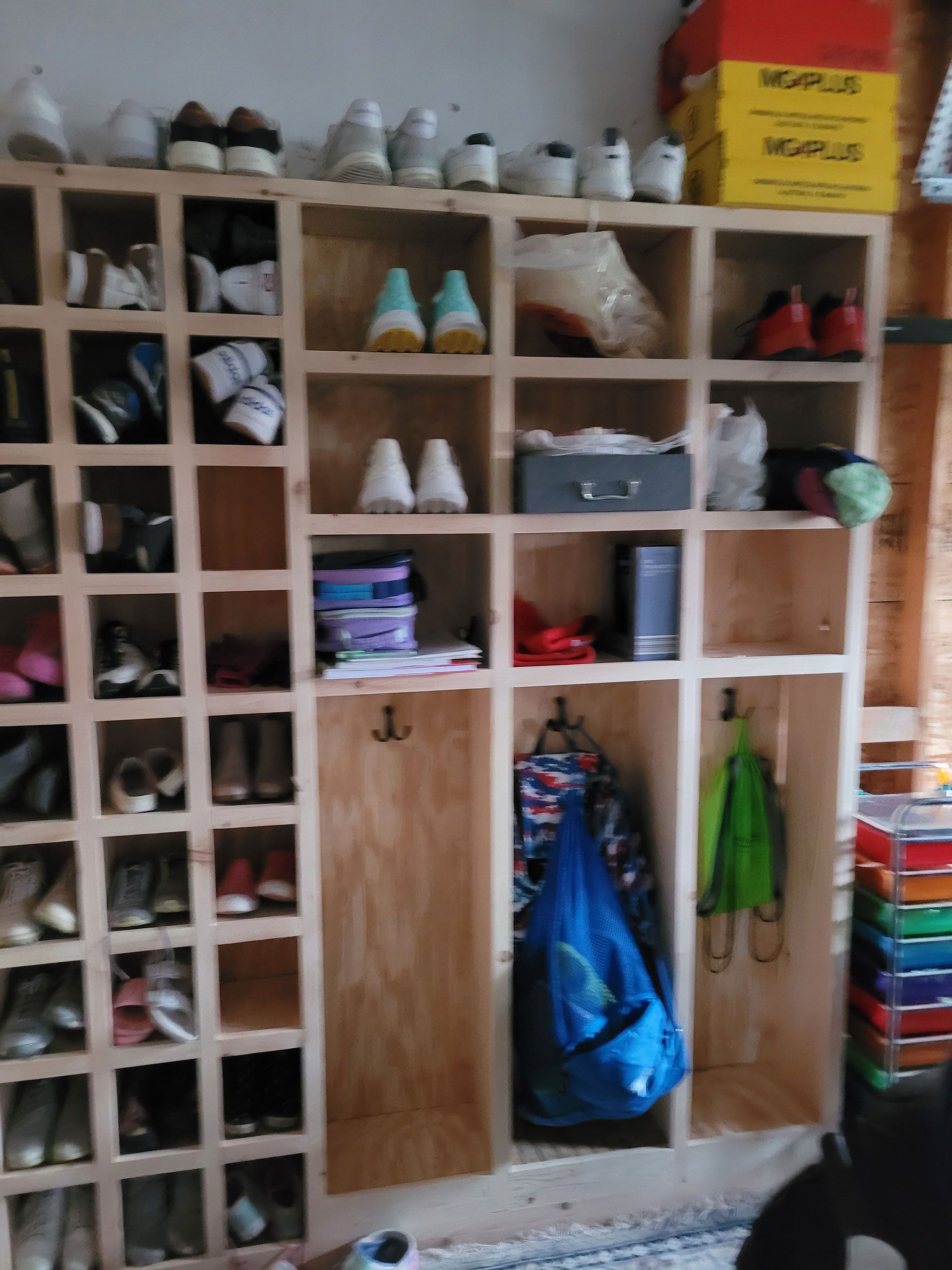 Wooden shoe and storage organizer filled with shoes, bags, and boxes.