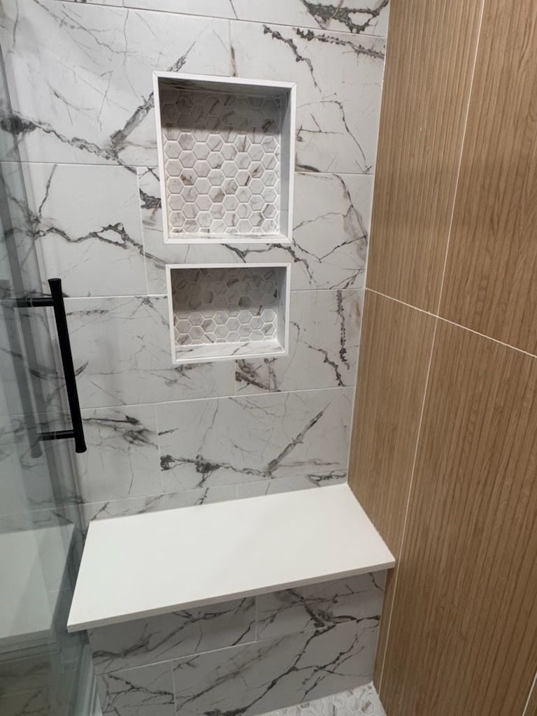 Shower interior with marble-patterned tile, two built-in storage niches with honeycomb tile, and a built-in bench.