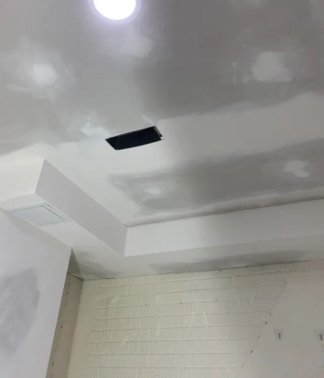 Ceiling construction with recessed light, vent, and soffit; unfinished drywall and primer.