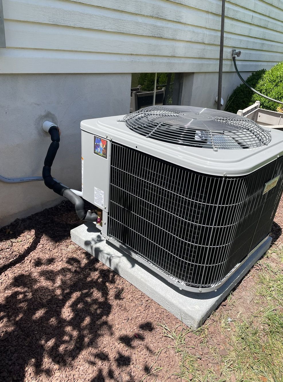 A large air conditioner is sitting outside of a house.