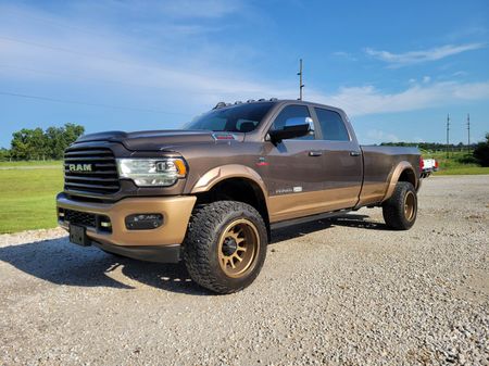 A brown ram truck is parked on a gravel road.