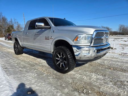 A silver ram truck is parked in the snow on a snowy road.