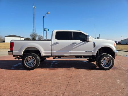 A white pickup truck is parked on a brick sidewalk.