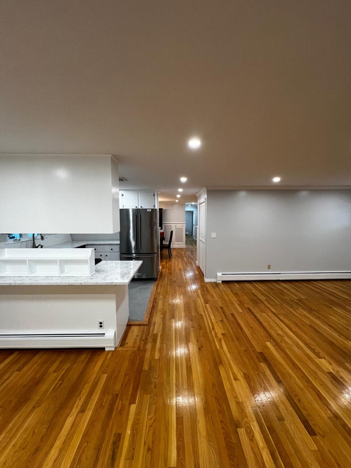 Open-concept living space with hardwood floors, white kitchen cabinets, and gray walls.