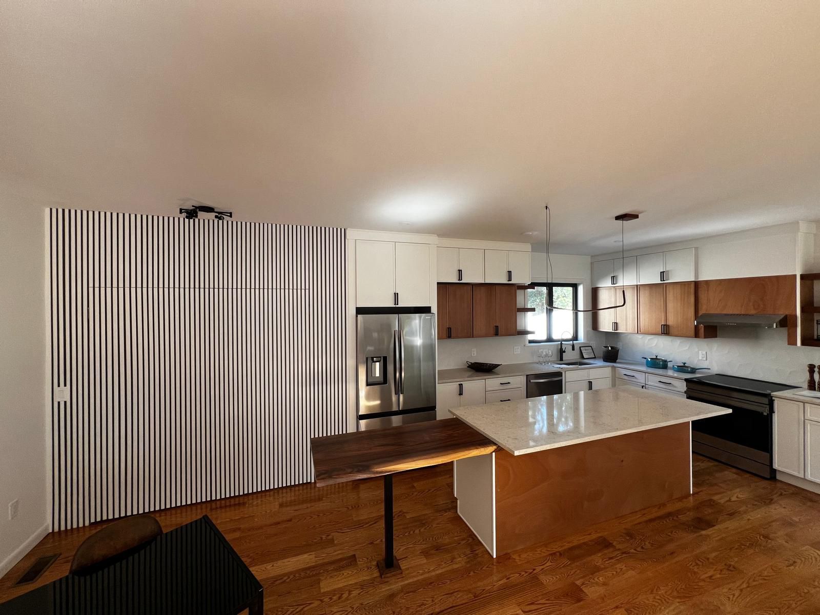 Kitchen with white and wood cabinets, island, and large storage with black and white striped design.