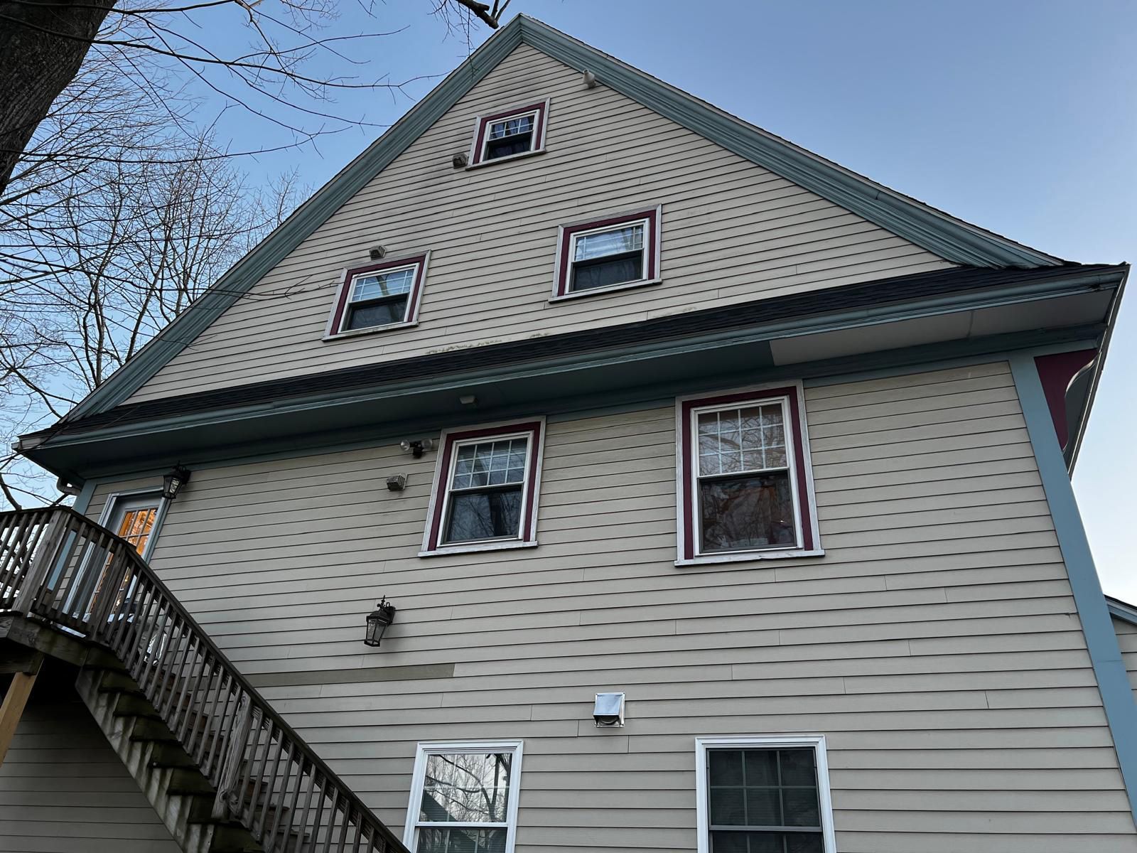 Tan house with multiple windows and a staircase on the side.