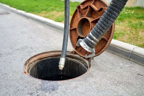 Open manhole with hose inserted for maintenance.
