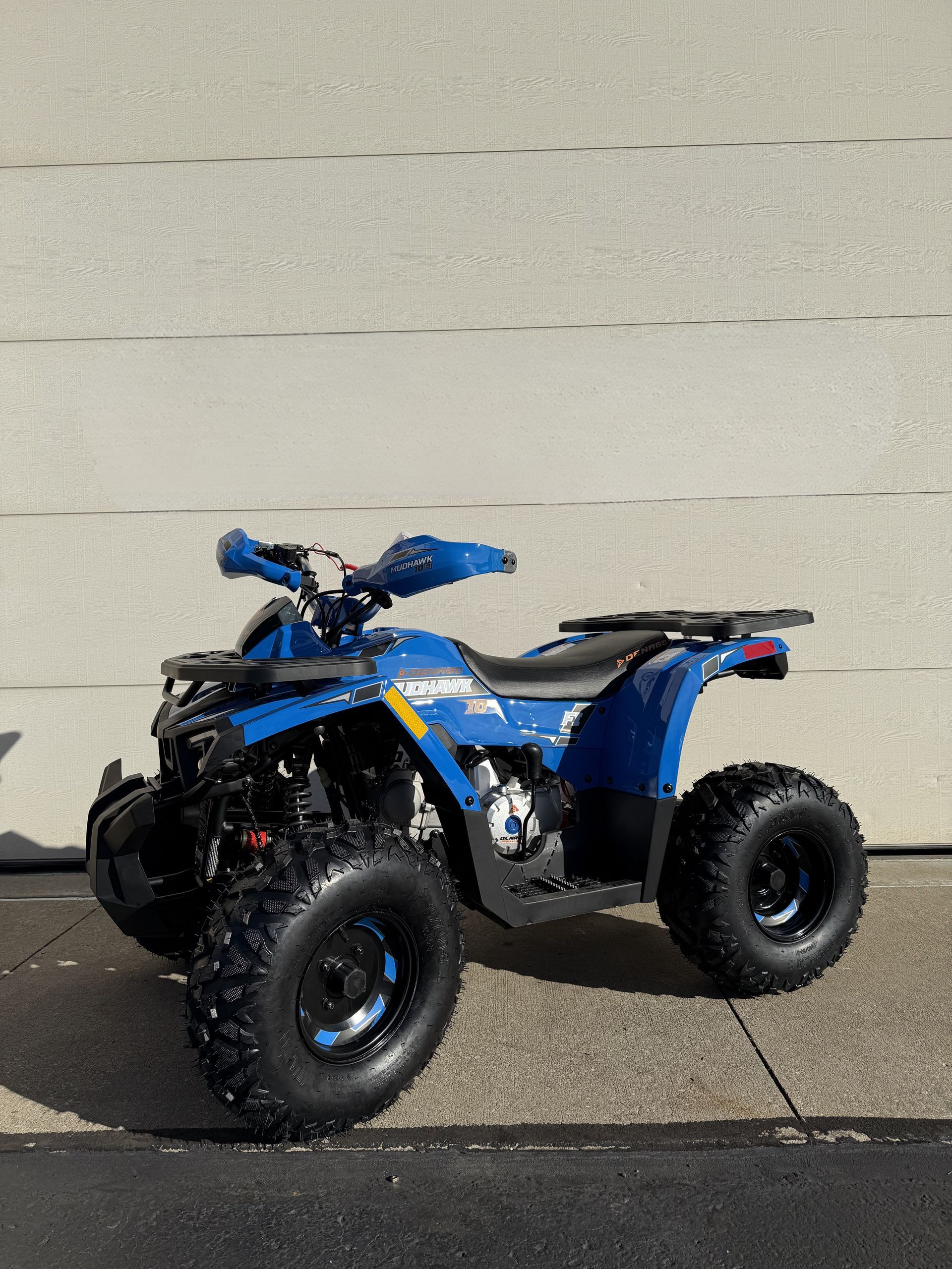 A bright blue all-terrain vehicle parked on a concrete surface against a light gray wall.
