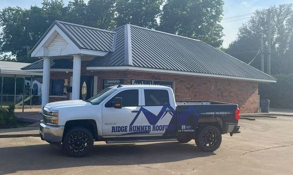 White truck with blue logo parked in front of a brick building.