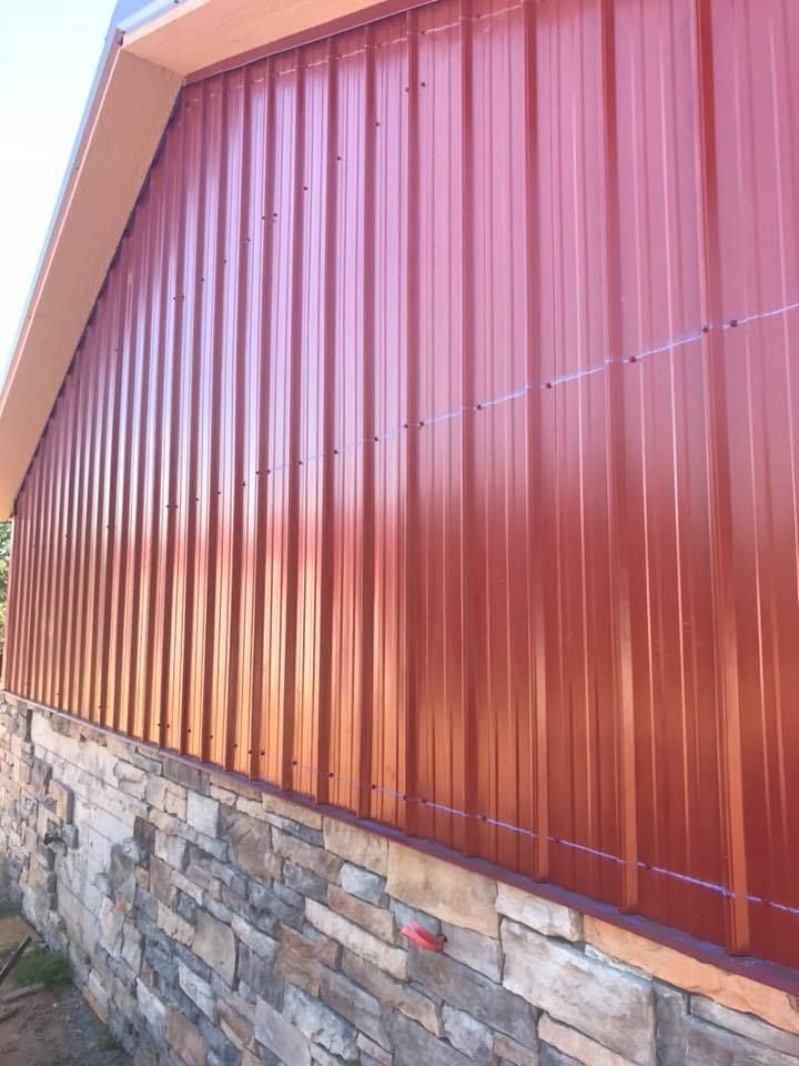 Red metal siding on a building with a stone foundation.