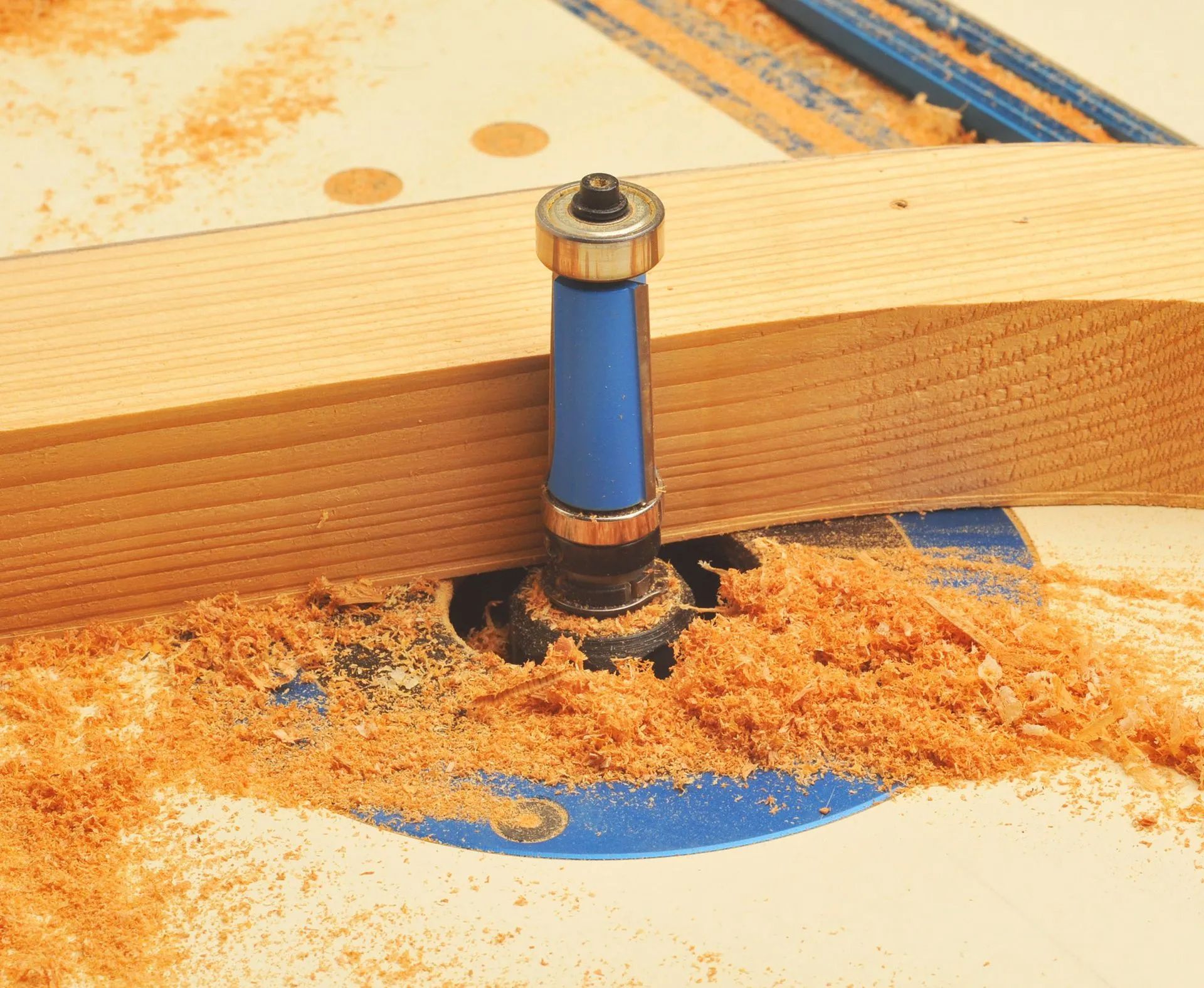 Wood router bit cutting a groove in a wooden board, with sawdust around it