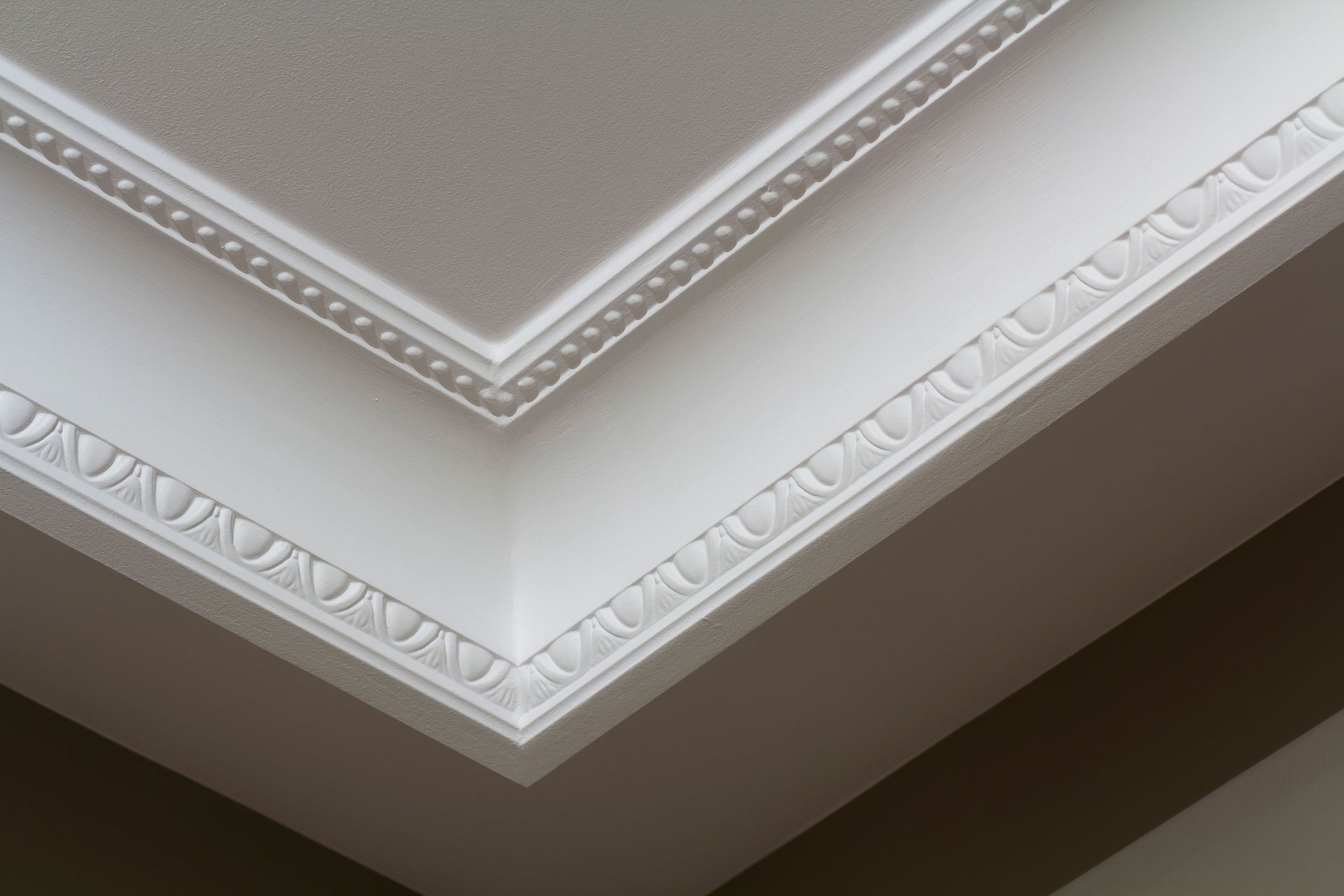 Decorative white crown molding on a corner ceiling with ornate trim details