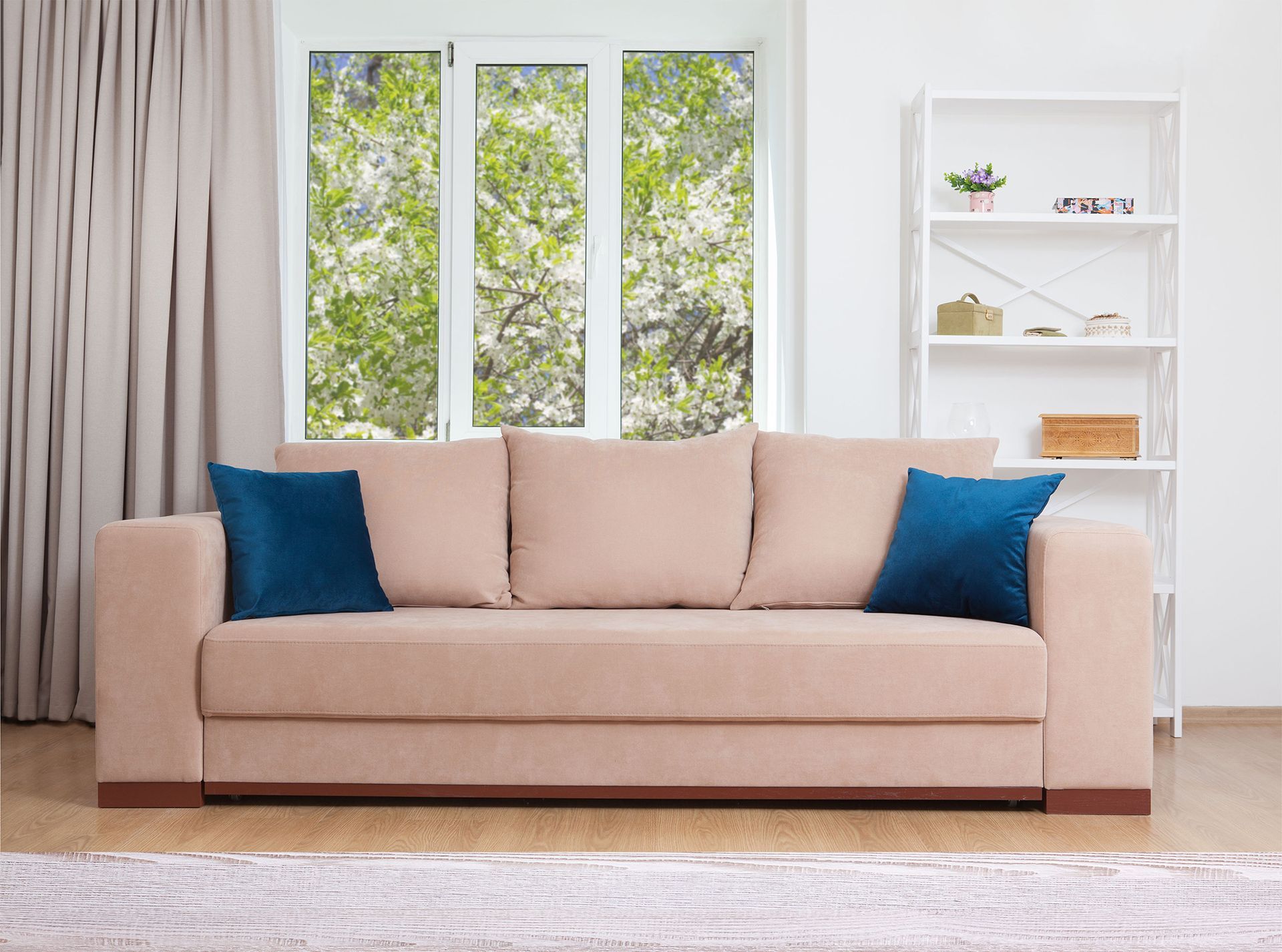 Beige sofa with blue cushions in a bright living room by a window and white shelving