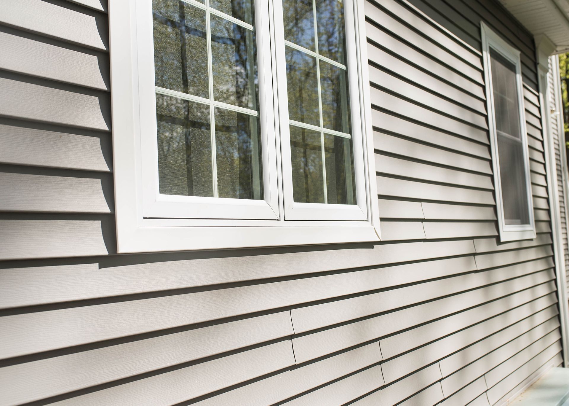 White house siding with a double window and a smaller side window in daylight
