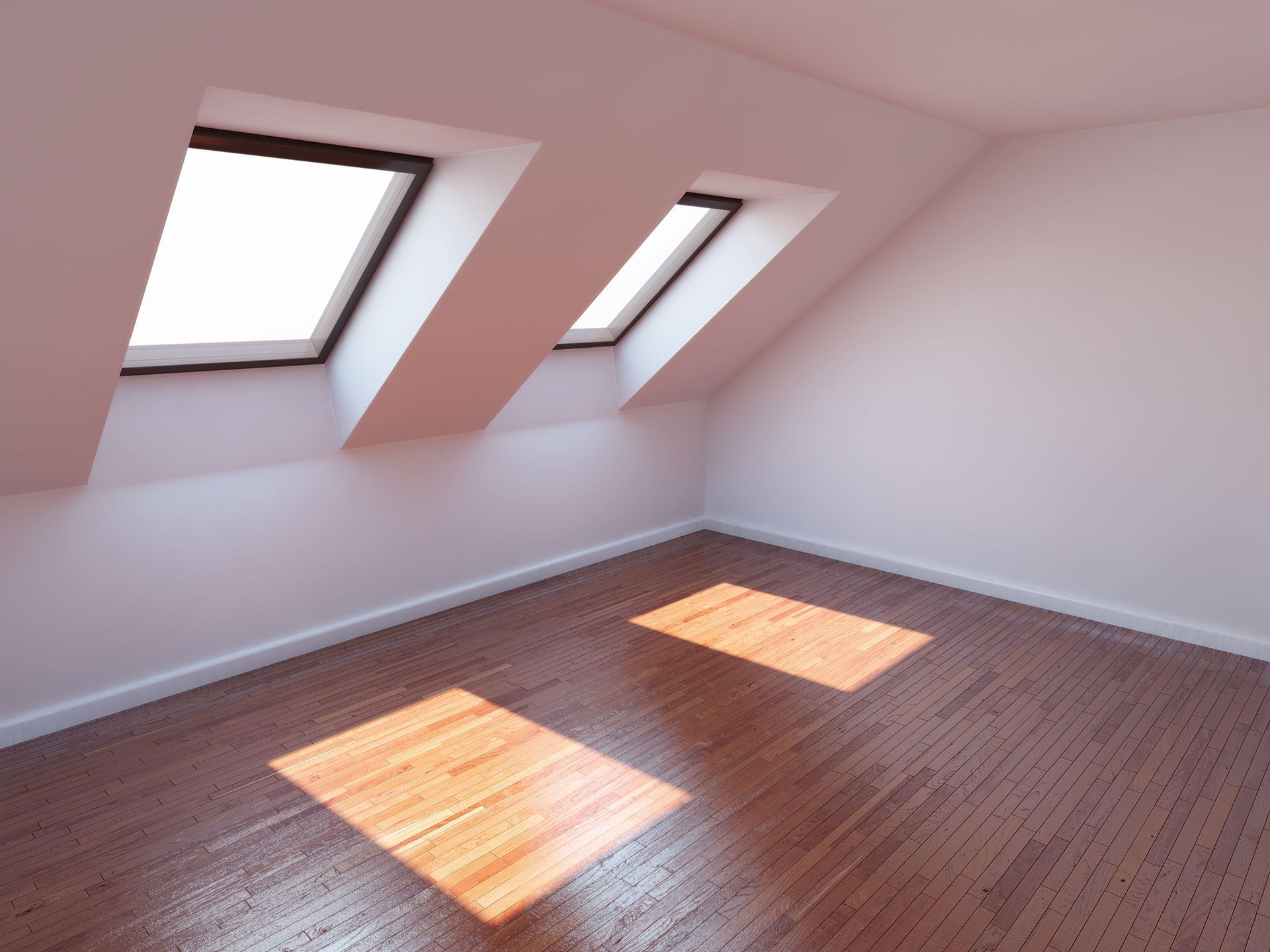 Empty attic room with slanted pink walls, two skylights, and sunlight on a wooden floor