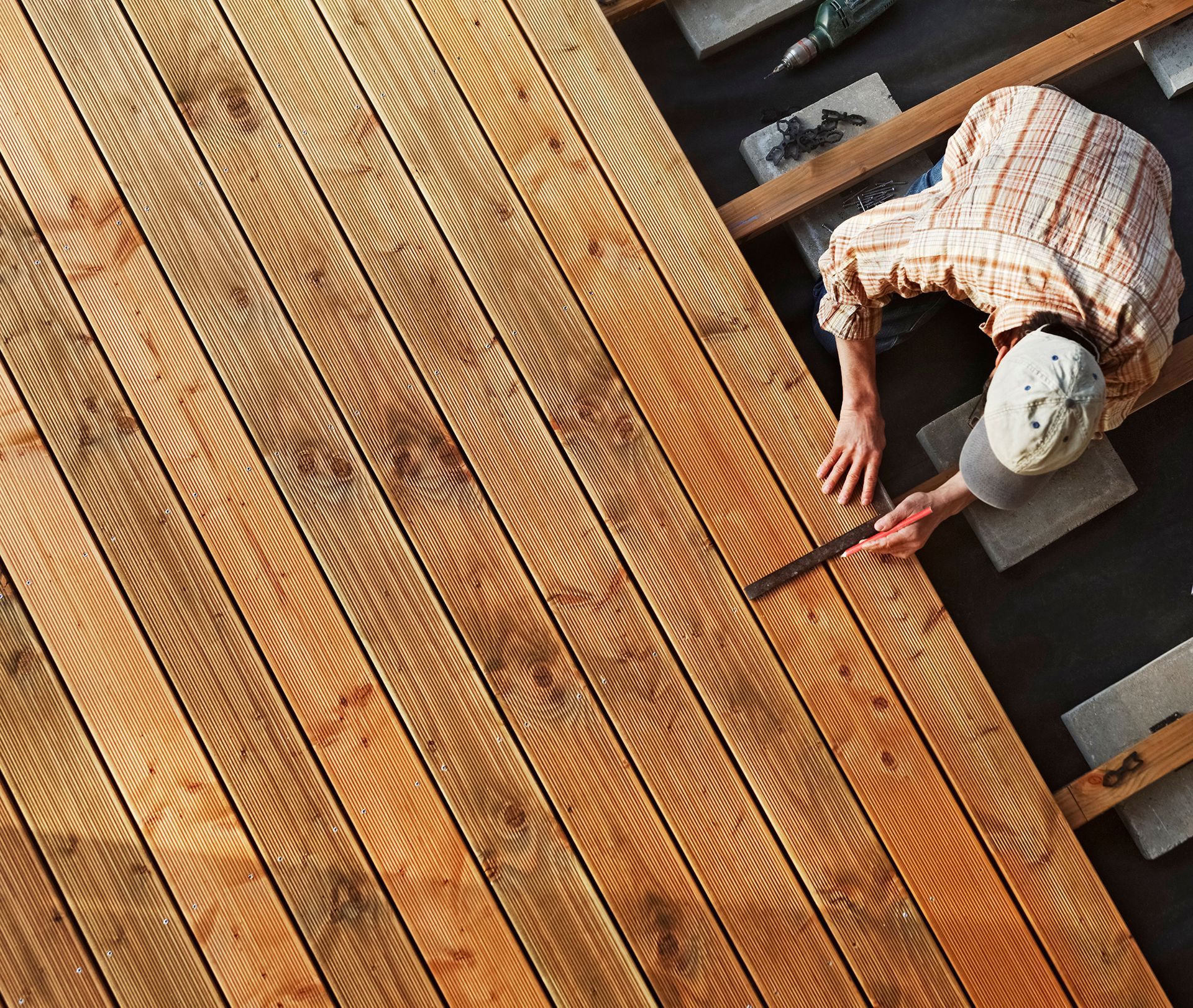 Worker painting a wooden deck with a brush