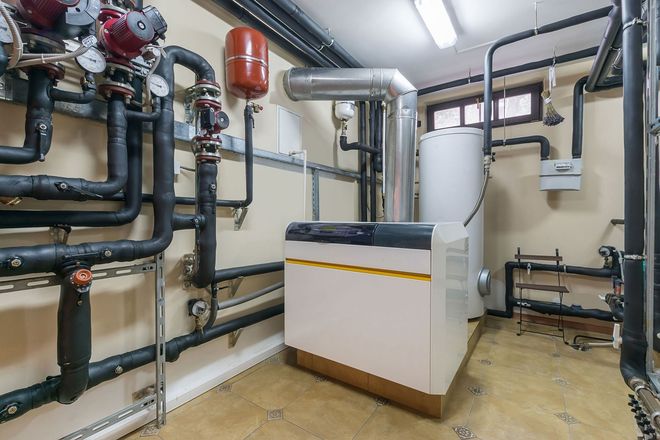 Mechanical room with pumps, pipes, and a large white boiler unit