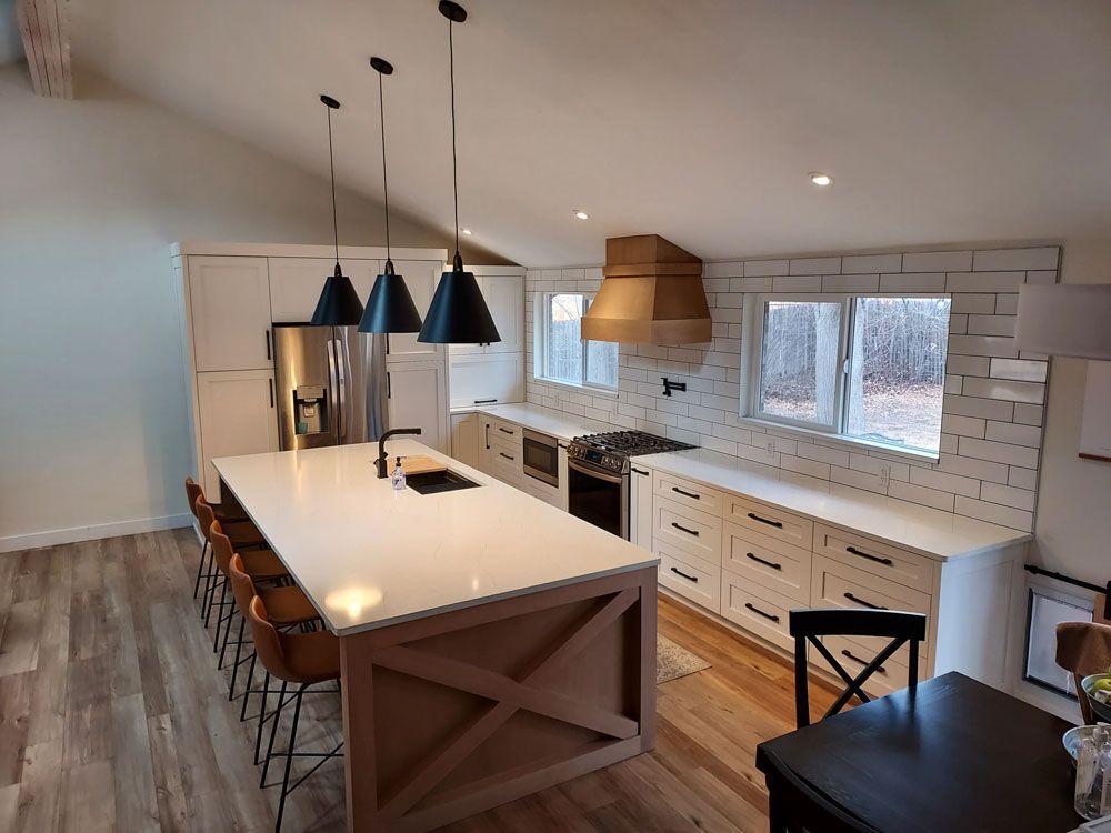 A kitchen with white cabinets, stainless steel appliances, and a large island