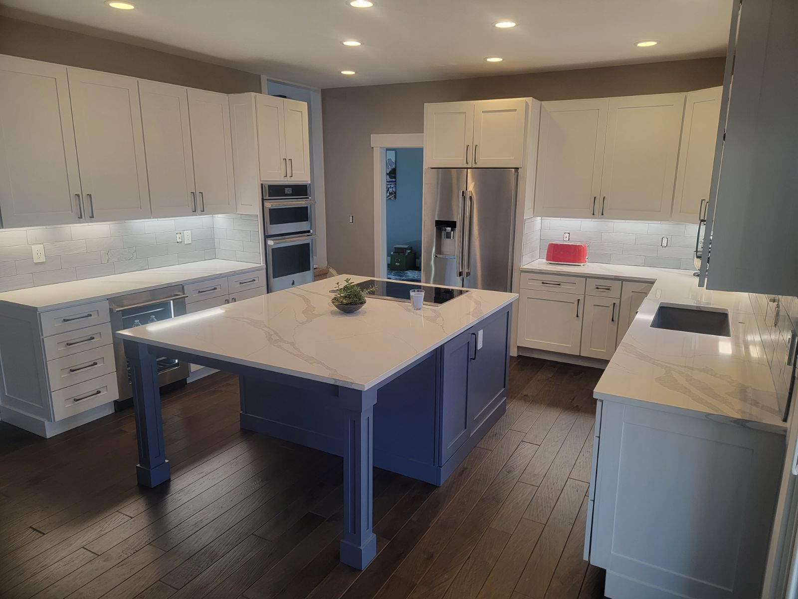 A kitchen with white cabinets and a large island in the middle