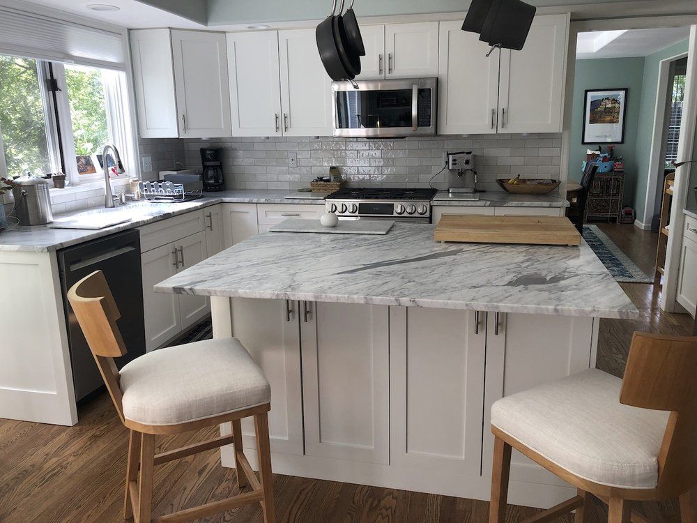A kitchen with white cabinets and a marble counter top