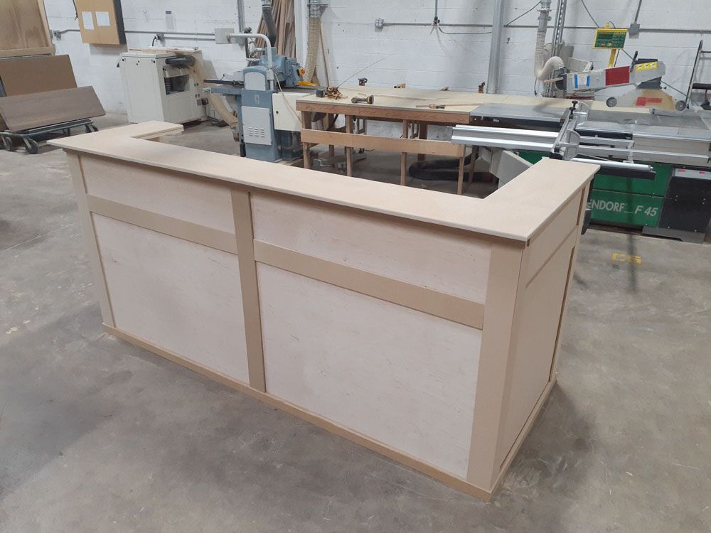 A large wooden counter is sitting in a room with a lot of machinery