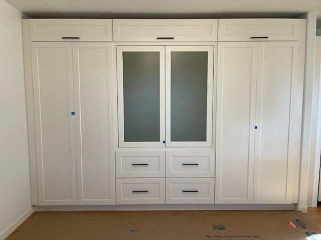 A room with a lot of white cabinets and drawers