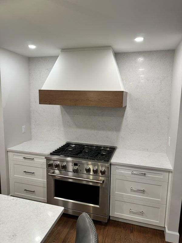A kitchen with a stove and a hood above it