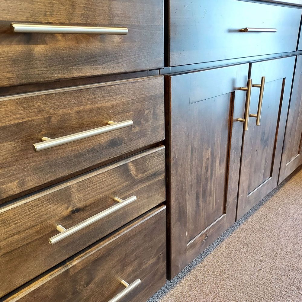 A kitchen with wooden cabinets and drawers with brass handles