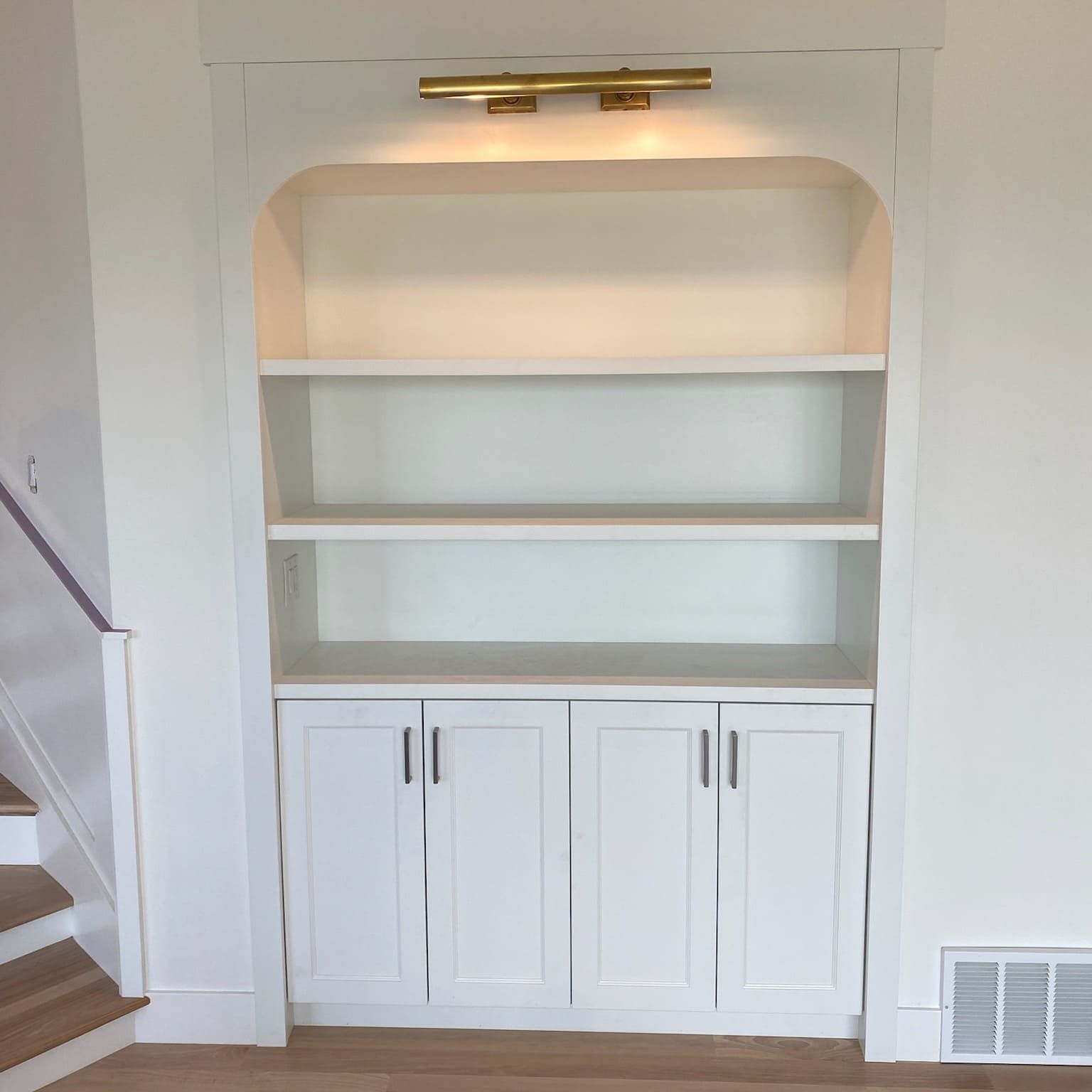 A white bookcase with stairs in the background