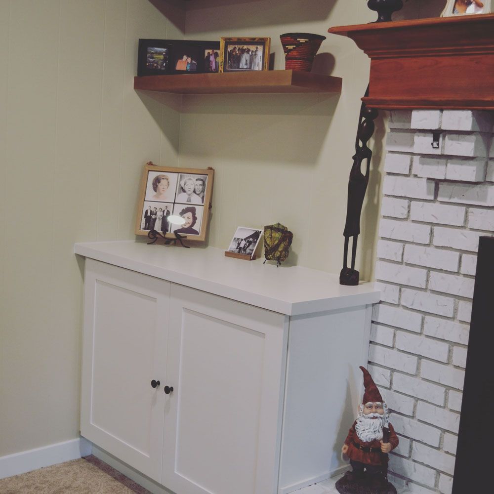 A living room with a fireplace and a shelf with pictures on it
