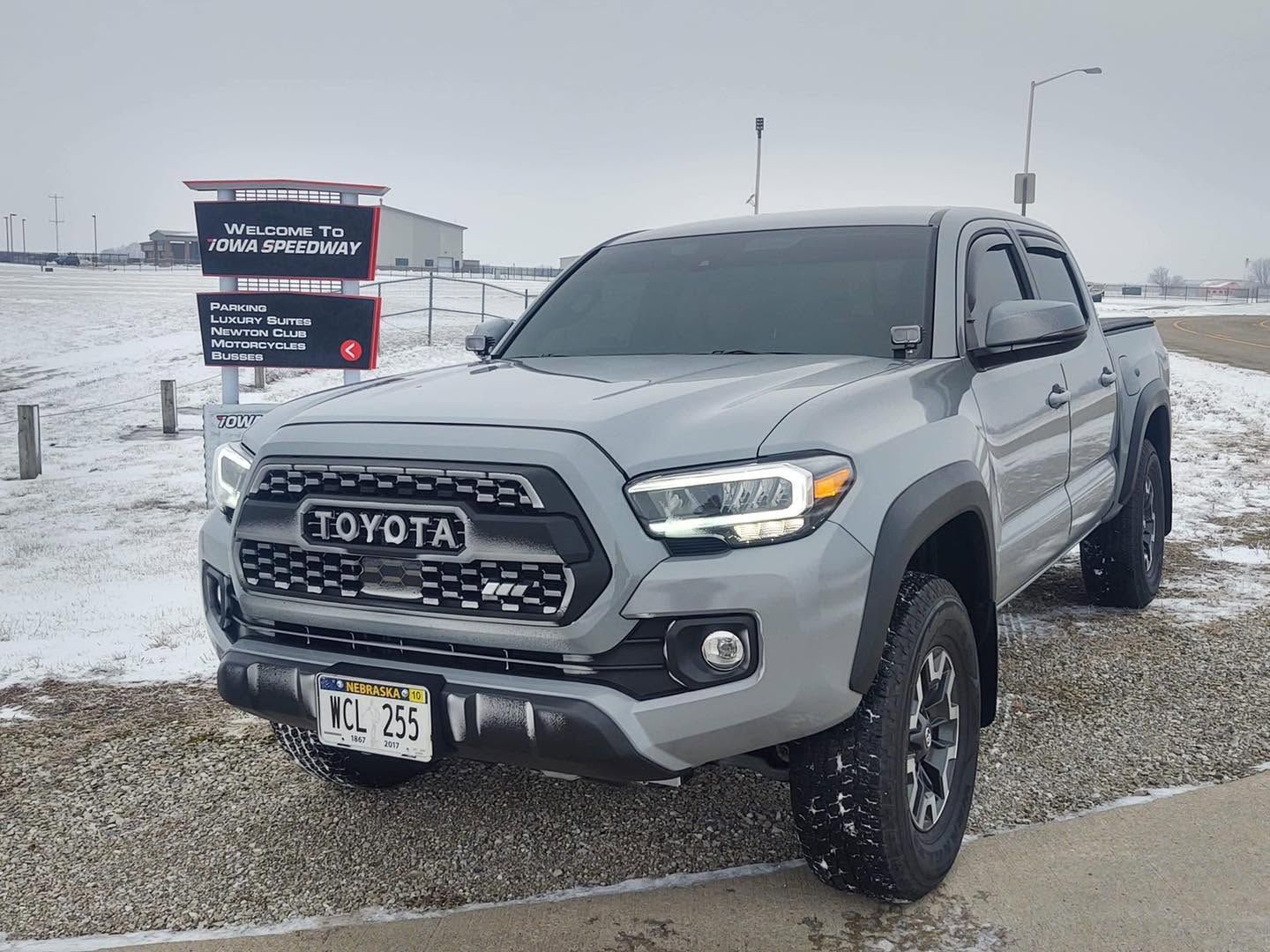 Gray Toyota pickup parked on a snowy roadside near a sign in a winter landscape