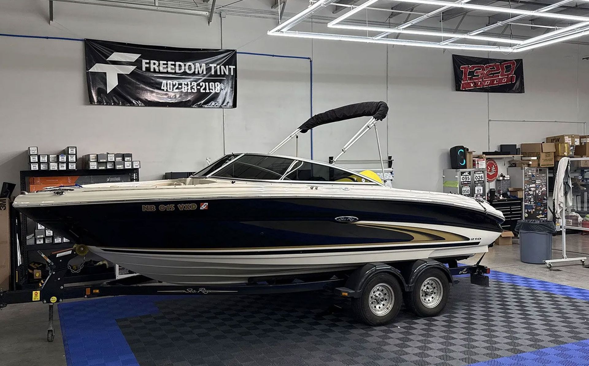 Black and cream speedboat on a trailer inside a showroom with blue carpeted floor