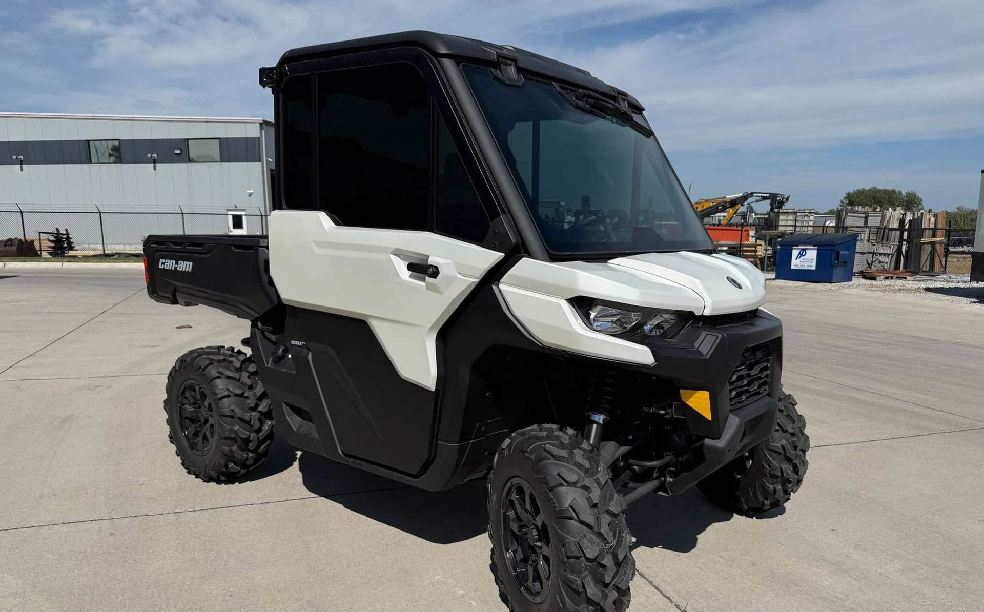 White and black off-road utility vehicle parked on a concrete lot under a clear sky