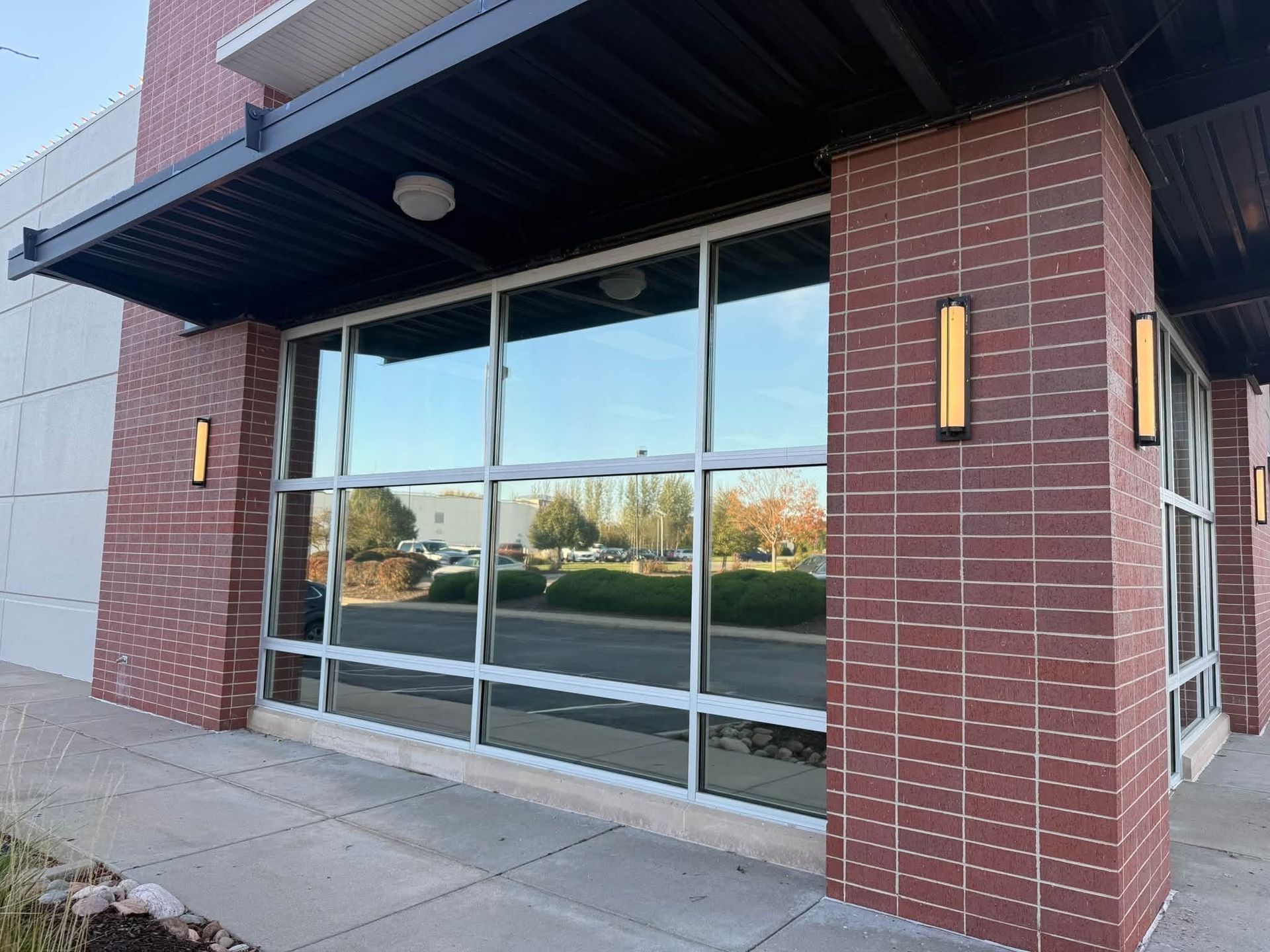 Storefront entrance with glass doors, brick columns, and dark awning on a sidewalk