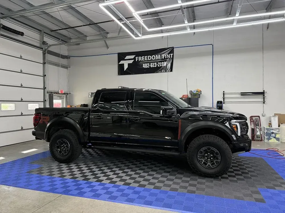 Black lifted pickup truck in a garage on a blue checkered floor