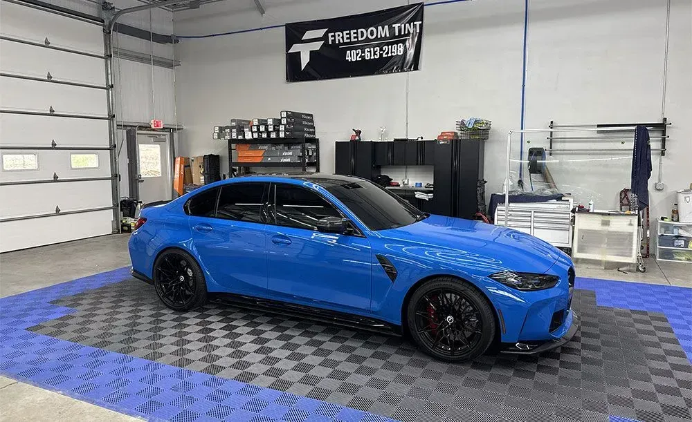 Blue sports sedan in a garage workshop with a black banner on the wall